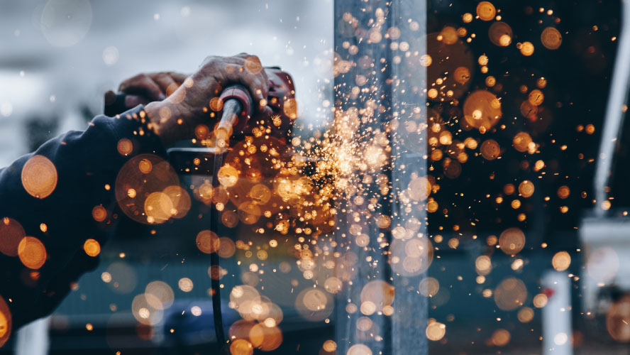 A person welding sparks on a metal pole, creating a strong bond between the materials.