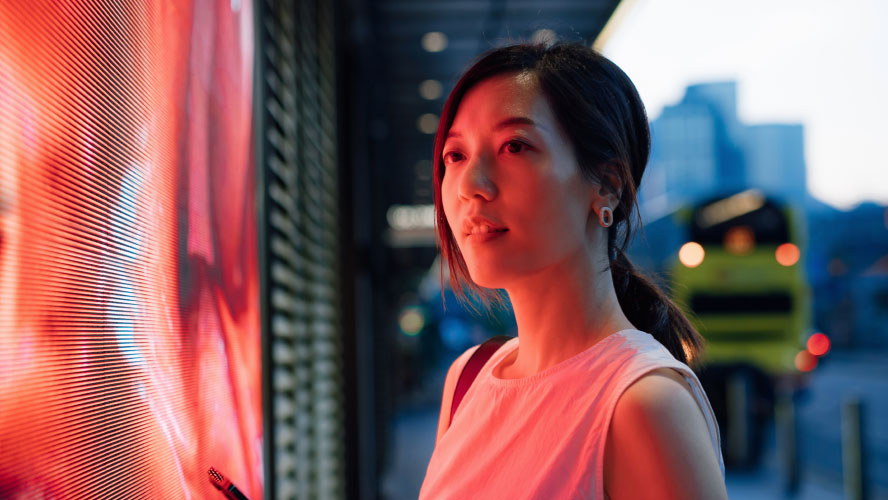 A woman standing in front of a large screen, presenting confidently to an engaged audience.