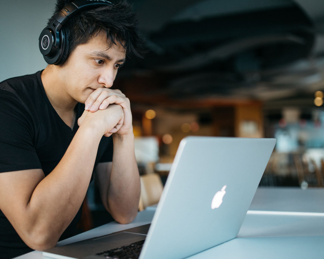 A man working on his laptop with headphones on.