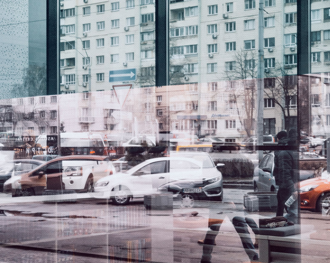 Reflection of pedestrians walking in front of a building.