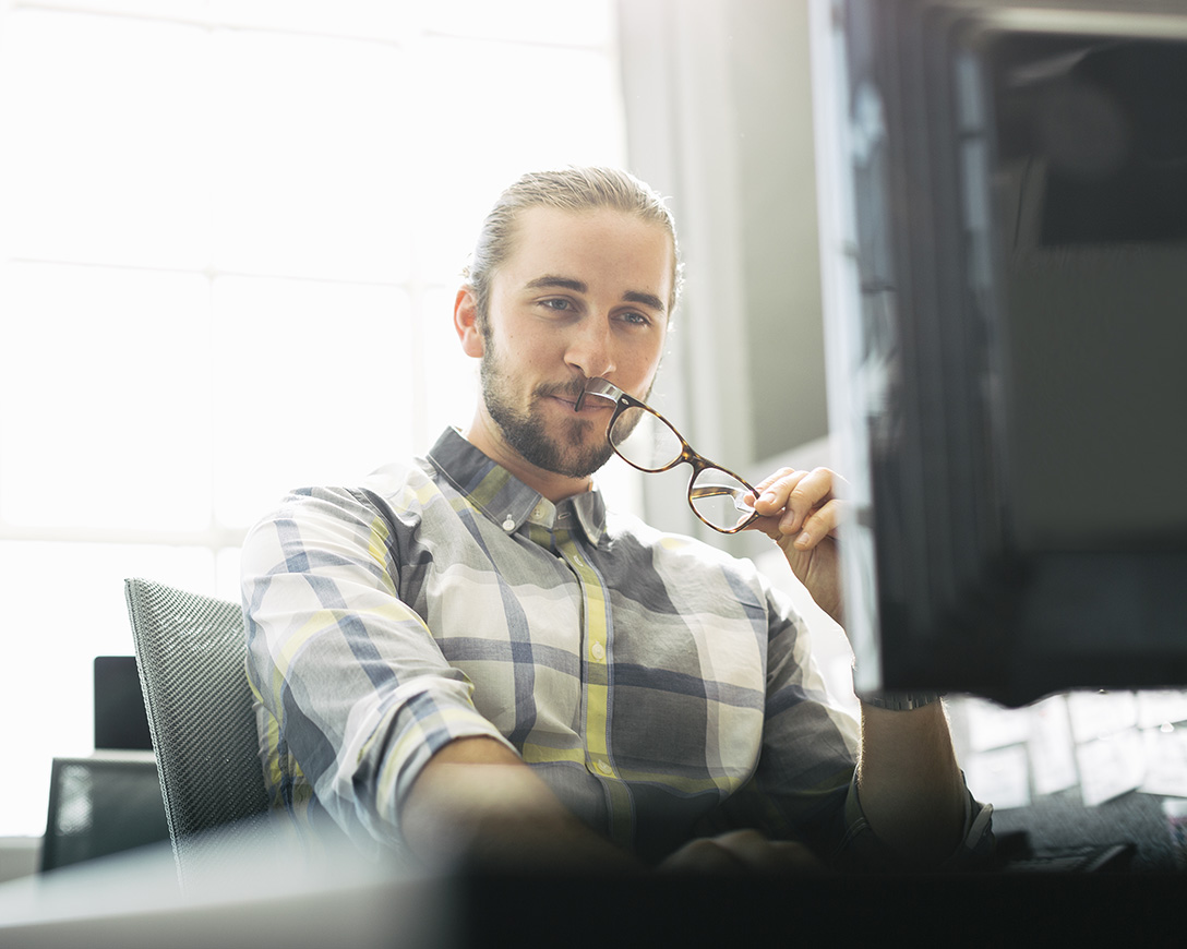 Performance - A man seated at a desk focuses on his monitor