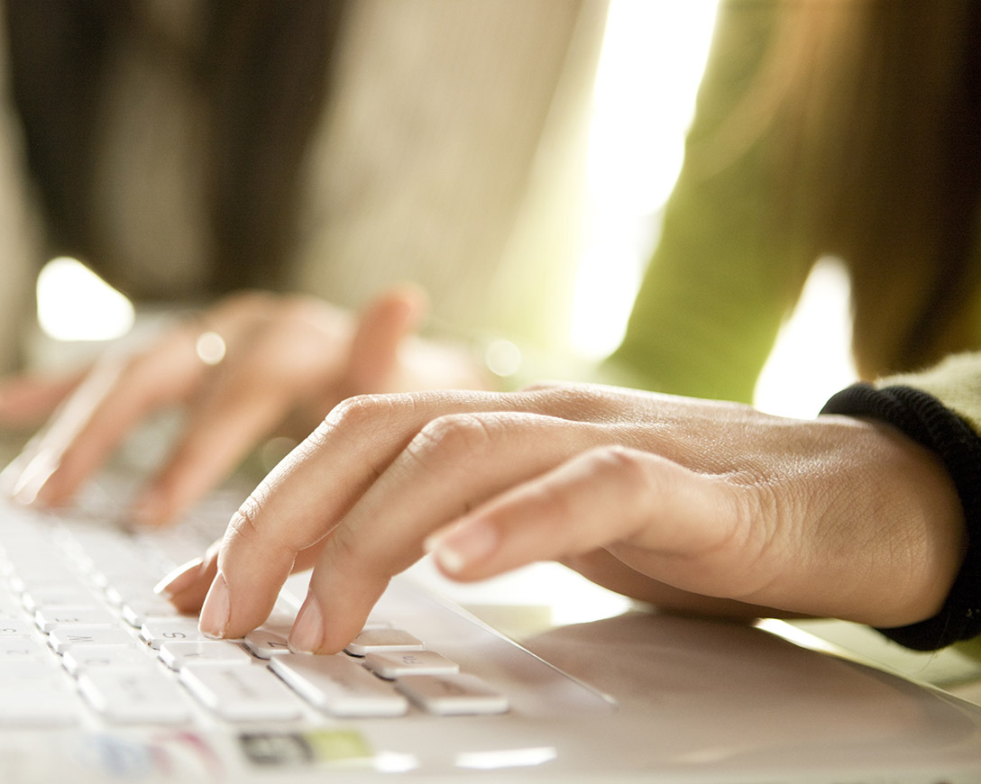 Marketplace – A woman in a green sweater types on a keyboard