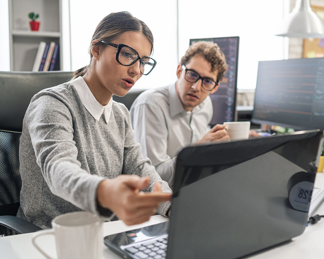 Database – Two IT techs confer about the data on a laptop