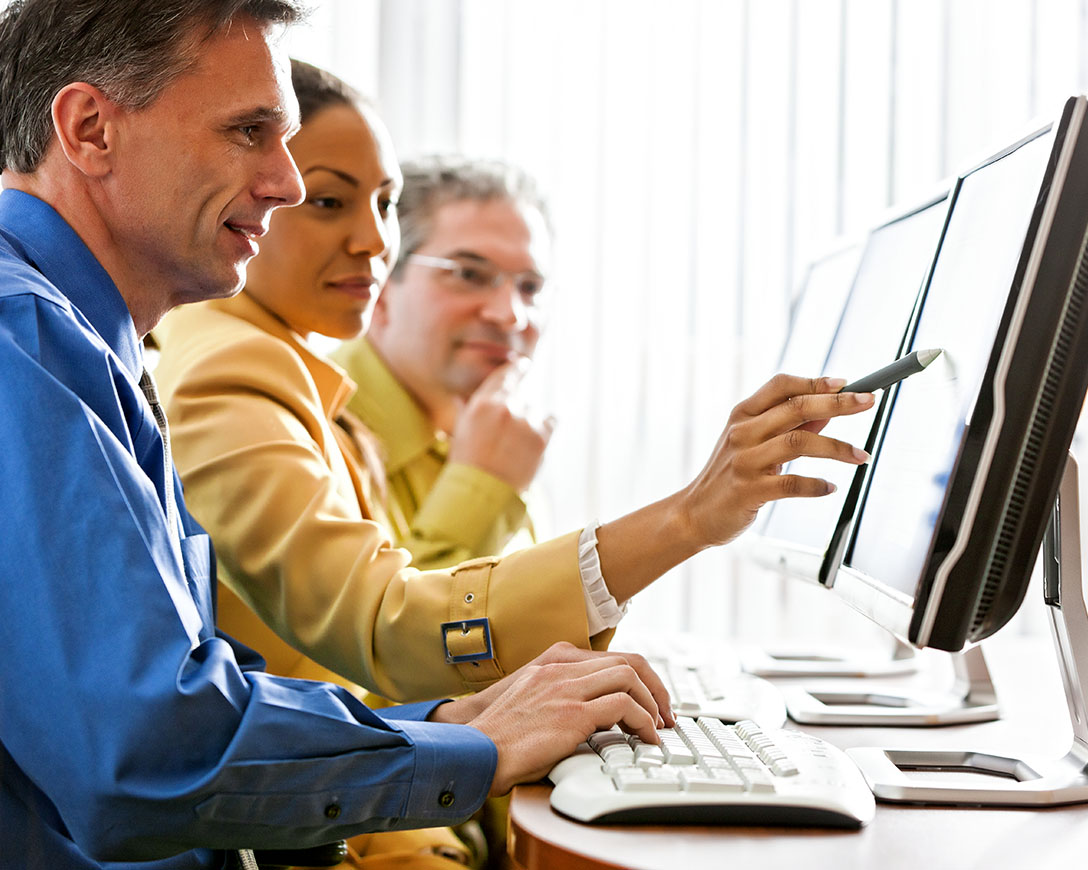 Flexibility – Three colleagues work together to make selections on a desktop computer