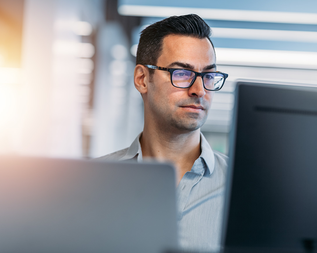 Ransomware - A clean-cut man with glasses focuses intently on his computer monitor