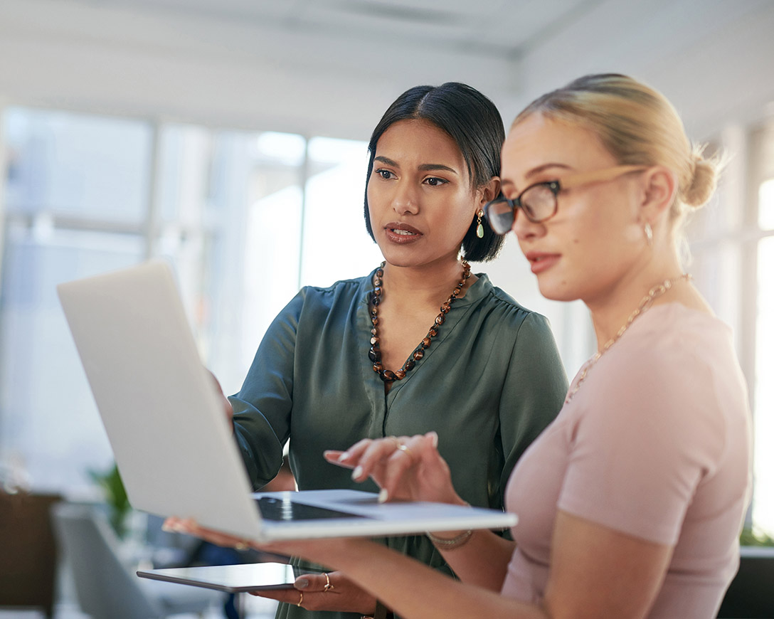 Backup – Two colleagues are focused on a laptop in a modern office